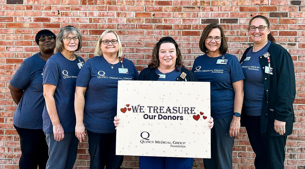Quincy Medical Group Foundation Employees holding a sign that says We Treasure Our Donors