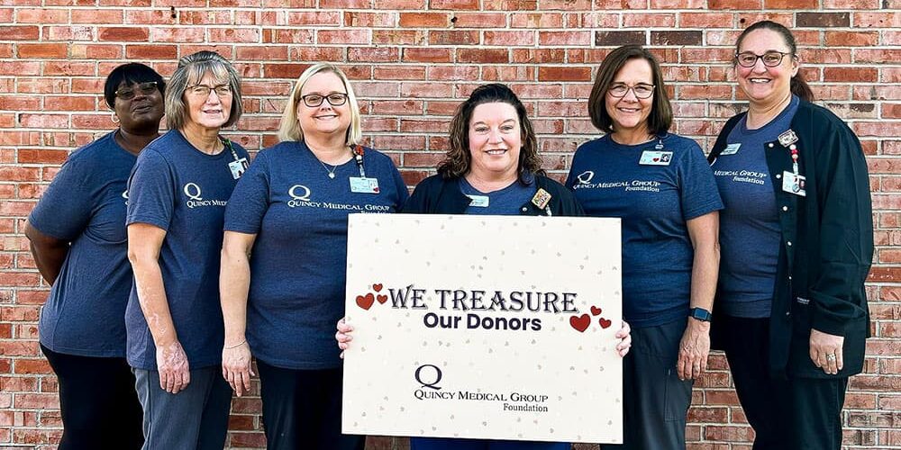 QMG-Foundation-Board-Treasure-Donors Quincy Medical Group Foundation Employees holding a sign that says We Treasure Our Donors
